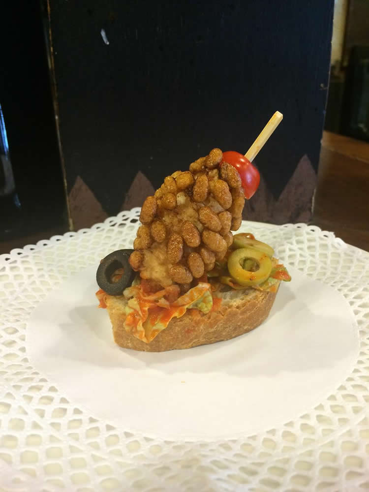 ¿Qué ye esto? (Restaurante El Cuera). Chipirón rebozado en arroz inflado sobre juliana de lechuga con salsa del piquillo, tomates cherry y aros de aceitunas.