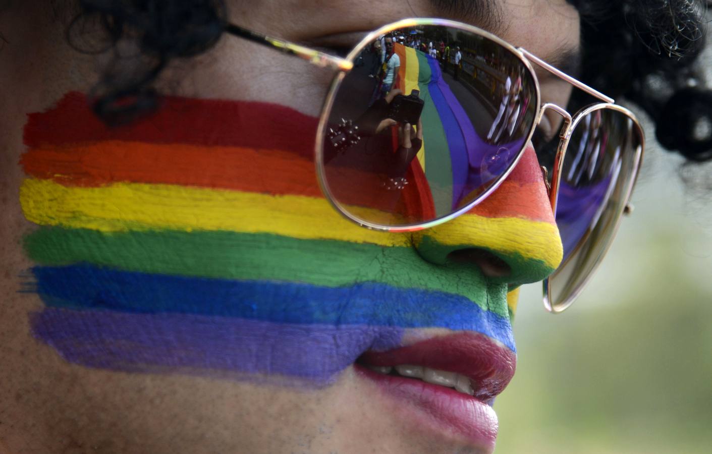 La bandera del orgullo gay se refleja en las gafas de un participante en el desfile del Orgullo Gay en Medellín -Colombia.