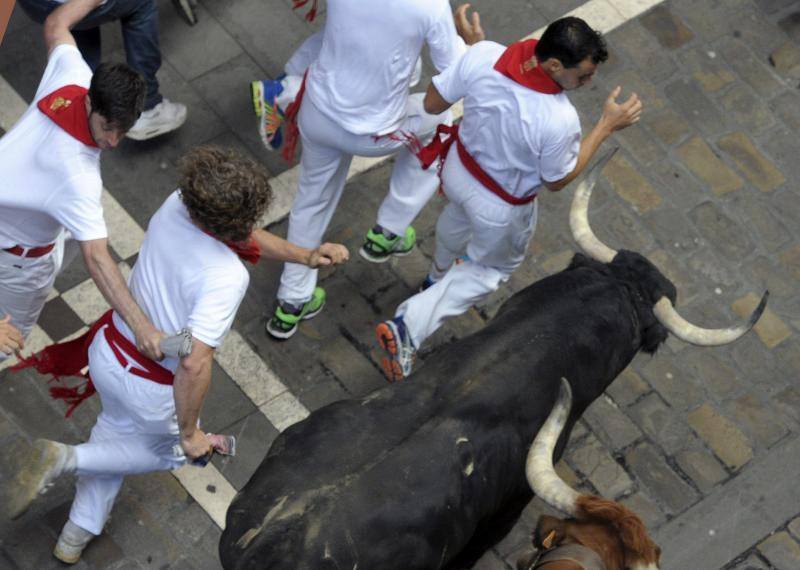 Los mosos corren junto a los toros durante el encierro.