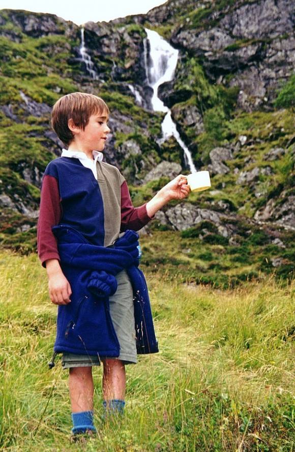 Agua en cascada. La taza no deja ver el final de la cascada y parece que este niño esta llenando el recipiente