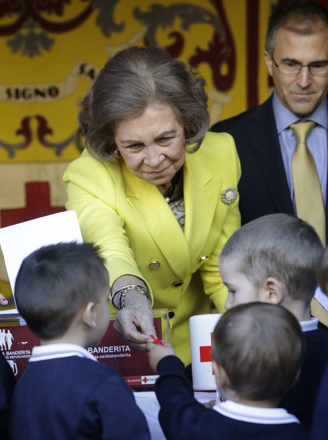 La reina Sofía entrega una banderita a un grupo de escolares en la mesa de cuestación de Cruz Roja.