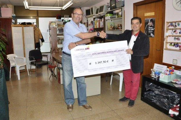 Francisco Javier García, de Asempa, recibe el cheque de manos del presidente de los rotarios, Rafael Martínez. 