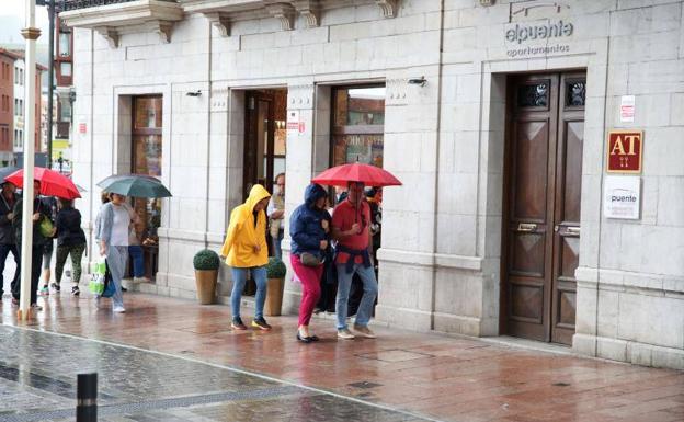 Los turistas, bajo el paraguas, en Llanes. 