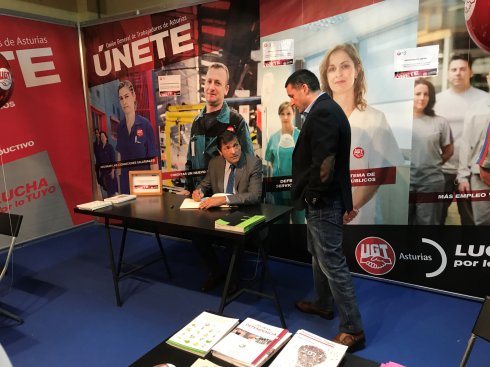 Javier Fernández firma en el libro de visitas del estand de UGT en la FIDMA, ante el secretario general del sindicato en Asturias. 