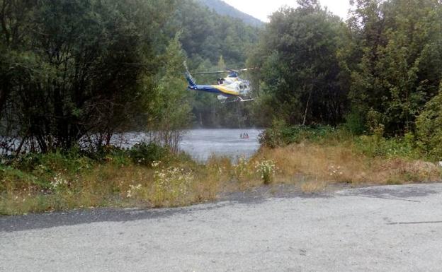 Un helicóptero carga agua para la extinción del fuego.