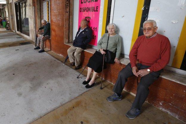 Varios vecinos optan por sentarse en el exterior de un local comercial ante la falta de bancos y demás mobiliario público. 