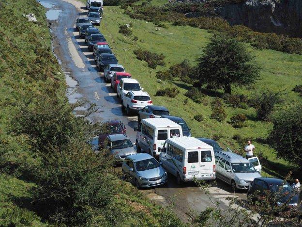 Coches estacionados en un lateral de la carretera provocaron atascos a la salida y entrada del aparcamiento de La Tiese, junto al lago Ercina. 