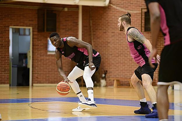 Romaric Belemene bota el balón ante su compañero Drew Maynard en el entrenamiento. 
