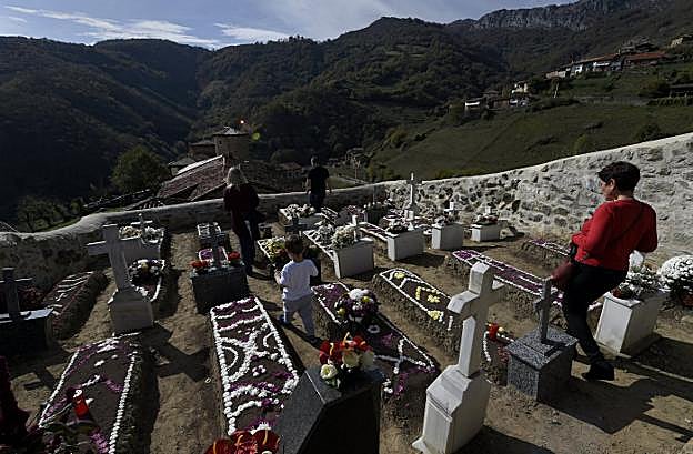 Un grupo de vecinos, ayer, en el cementerio de Bandujo. A la izquierda, vista general del camposanto de la localidad. 