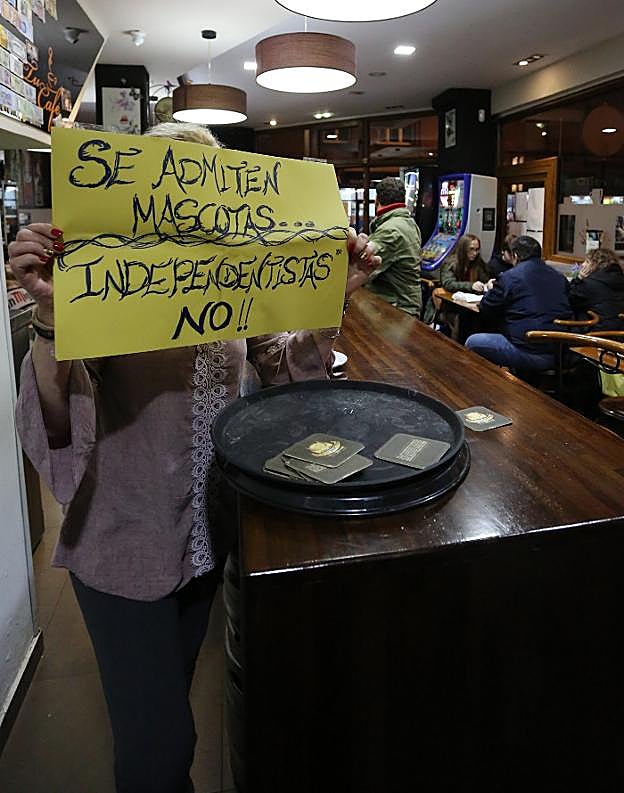 La propietaria del bar muestra el polémico cartel. 