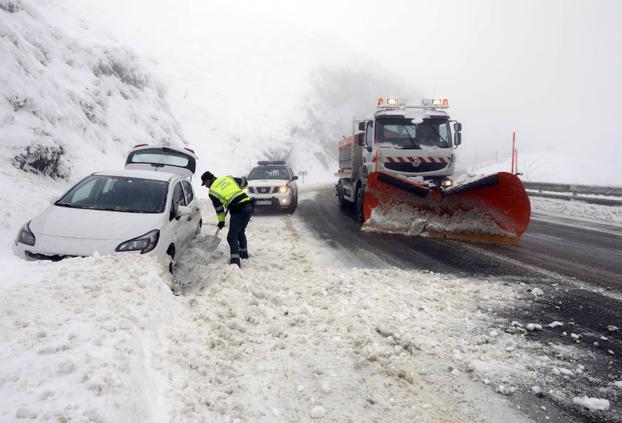 Un guardia civil retira nieve con una pala para ayudar a un conductor que se quedó atrapado.