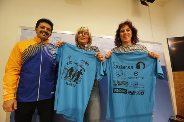 La concejala de deportes, Ana Hevia, flanqueada por el presidente y la vicepresidenta del Avilés Atletismo, David Sotura y Estrella Benavides, con la camiseta conmemorativa de la prueba. 