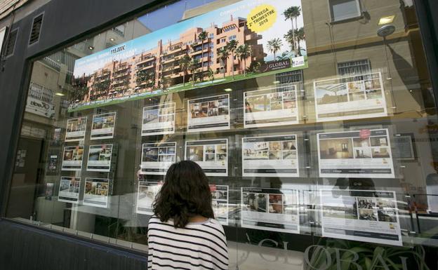 Uan joven mira las ofertas de pisos en una inmobiliaria.