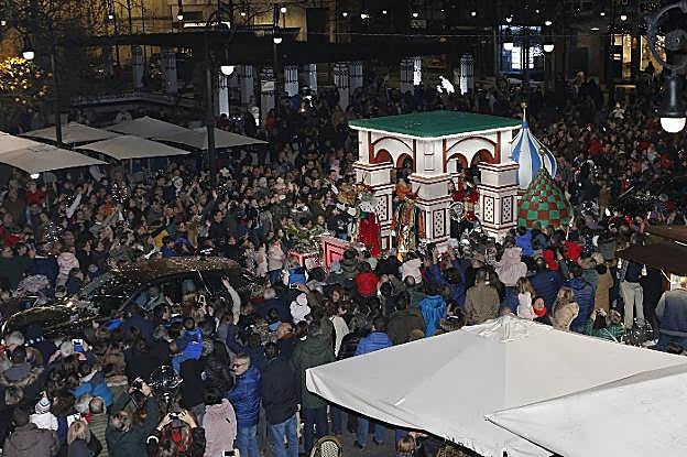 El Rey Melchor saluda a la multitud desde su carroza, mientras sus pajes lanzan caramelos para los niños. 
