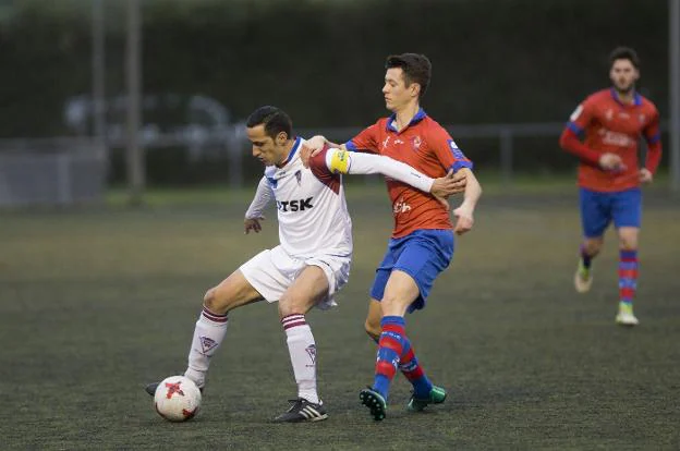 El capitán del TSK Roces y excearista Jimmy protege el balón ante Juan Menéndez. 