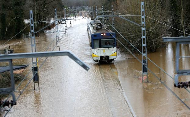 Siero. Un tren avanza por las vías, completamente inundadas, a la altura de Castañera. 