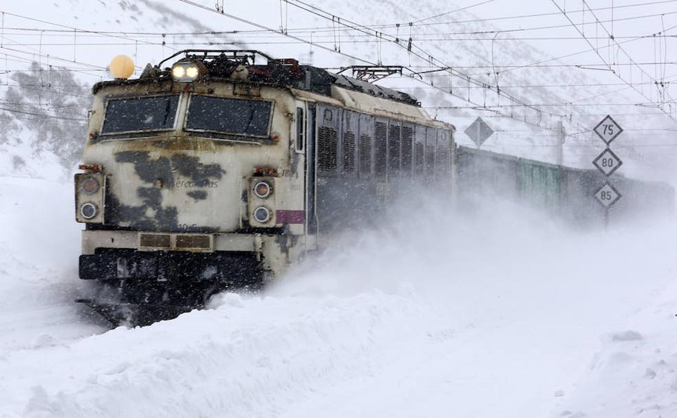 Un tren de mercancías de Renfe se abre paso entre la cantidad de nieve acumulada sobre la vía en Busdongo. 