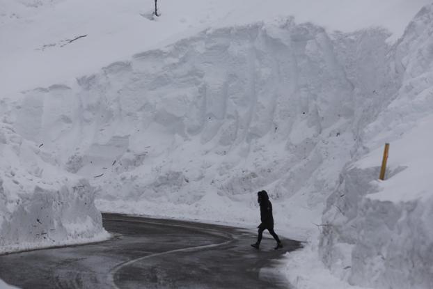 Una mujer camina entre paredes de nieve por la carretera al puerto de San Isidro. 