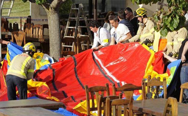 Operarios y bomberos retiran el castillo hinchable donde se produjo el accidente.