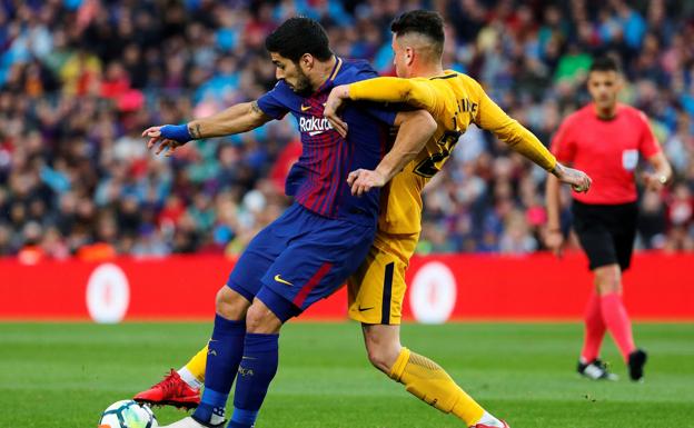 Luis Suárez pugna con José María Giménez ante Gil Manzano, atento, al fondo 