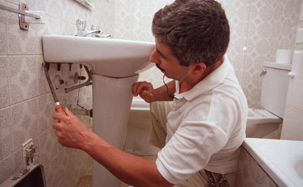 Un fontanero, colocando unas tuberías en una casa. 