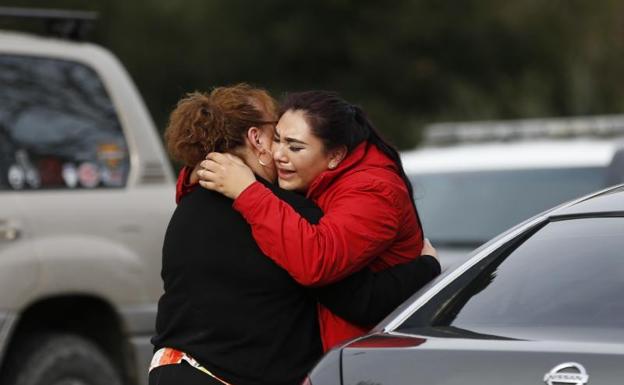 Dos mujeres se abrazan tras conocer el asesinato de tres empleadas del centro para veteranos.