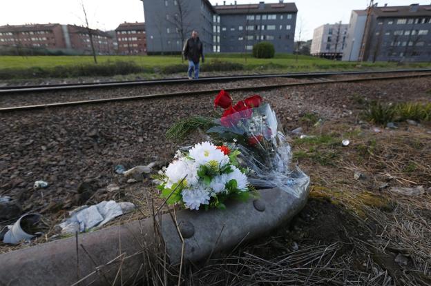 Un ramo de flores, en el lugar en el que el viernes perdió la vida J. F. C. Al fondo, un hombre cruza las vías. 