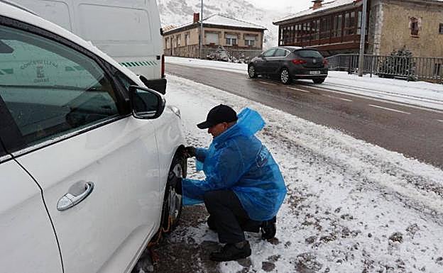 Imagen. Un conductor coloca las cadenas a su vehículo.