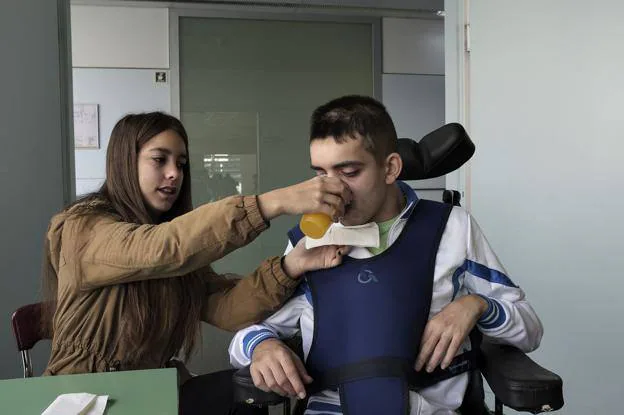 Marina ayuda a su hermano a beber un zumo de naranja en el Instituto Guttmann de Barcelona.