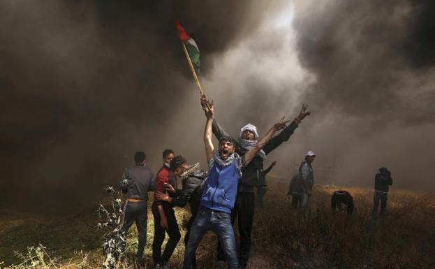 Dos palestinos protestan frente a las tropas israelíes en Gaza.