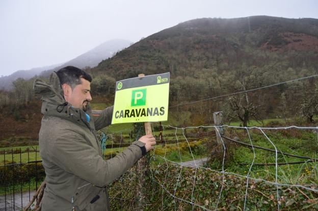 Víctor Manuel Álvarez coloca el cartel que señaliza la ubicación del aparcamiento de caravanas. 