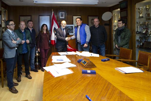 Antonio Corripio estrecha la mano de Christian Almirante tras la firma del primer convenio del Grupo. Abajo, tareas de desbroce en La Torriente. 