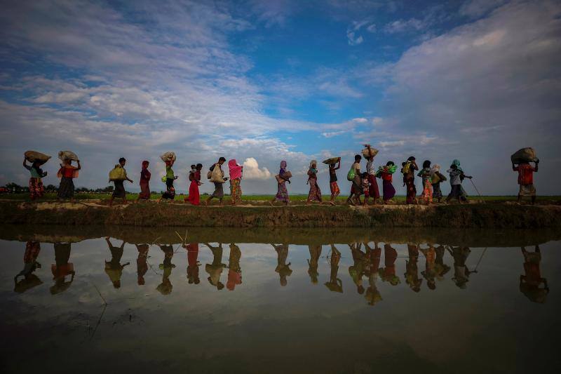 Refugiados rohinyás se reflejan en el agua de lluvia a lo largo de un terraplén junto a arrozales después de huir de Myanmar a Palang Khali, cerca de Cox's Bazar (Bangladés), el 2 de noviembre de 2017.