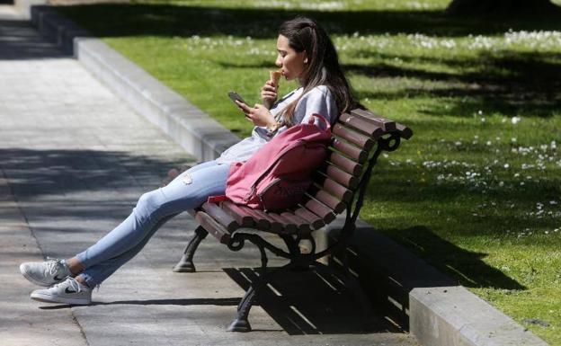 Una joven disfruta de un helado en un parque de Oviedo, donde las temperaturas alcanzaron los 26 grados. 