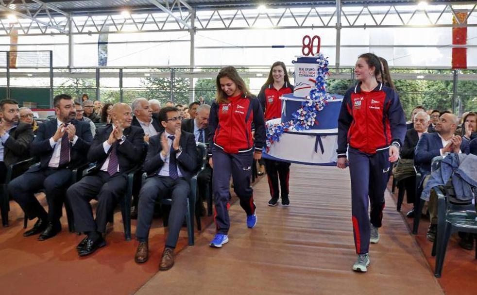 Cuatro cadetes del equipo de voleibol del Grupo, reciente campeón de España, cargan con la tarta conmemorativa del 80 aniversario