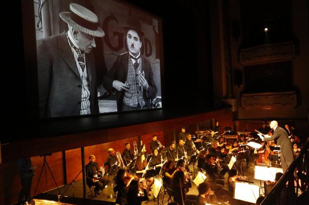 Mariano Rivas dirige a la orquesta con Chaplin en pantalla. 