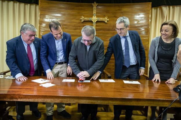 El abad de Covadonga, Adolfo Mariño, estampa el matasellos conmemorativo en la tarjeta. Le acompañan Ángel Iglesias, de la Sociedad Filatélica; el regidor cangués, José Manuel González; Ángel Pérez, director de zona de Correos; y Otilia Requejo, directora de Patrimonio del Principado . 