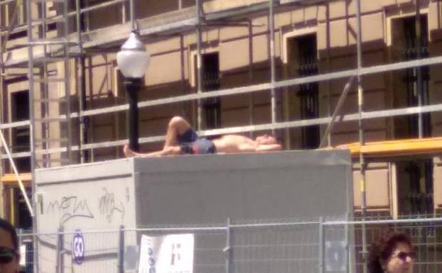 Un hombre toma el sol en la calle Tomás y Valiente de Gijón.