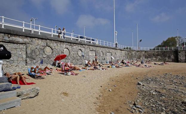 Gente tomando el sol en el Tosataderu de la playa de San Lorenzo.