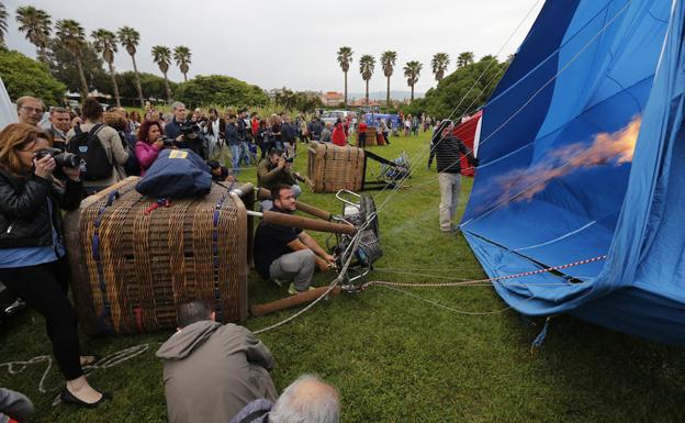 Imagen. El piloto de uno de los globos aerostáticos, rodeado de gente, 'suelta gas' para lograr la verticalidad de su aeronave.