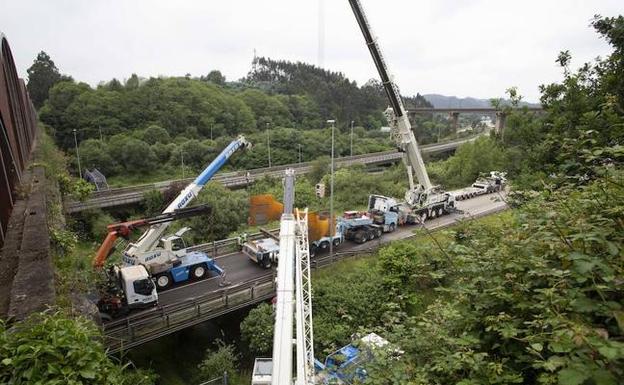 Varias grúas de gran tamaño trabajan sobre la pieza desprendida en uno de los carriles de la A-8. 