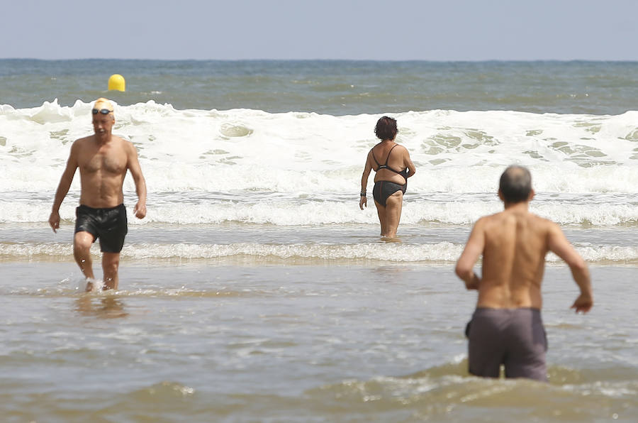 Las banderas amarilla y verde que luce la playa y la buena temperatura ya ha animado a algunas personas a pegarse un baño en el Cantábrico. 