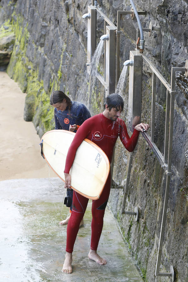 Las banderas amarilla y verde que luce la playa y la buena temperatura ya ha animado a algunas personas a pegarse un baño en el Cantábrico. 