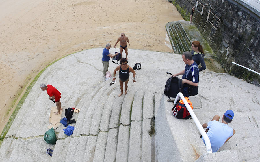 Las banderas amarilla y verde que luce la playa y la buena temperatura ya ha animado a algunas personas a pegarse un baño en el Cantábrico. 