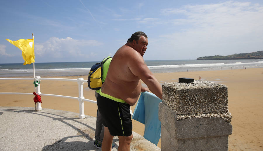 Las banderas amarilla y verde que luce la playa y la buena temperatura ya ha animado a algunas personas a pegarse un baño en el Cantábrico. 