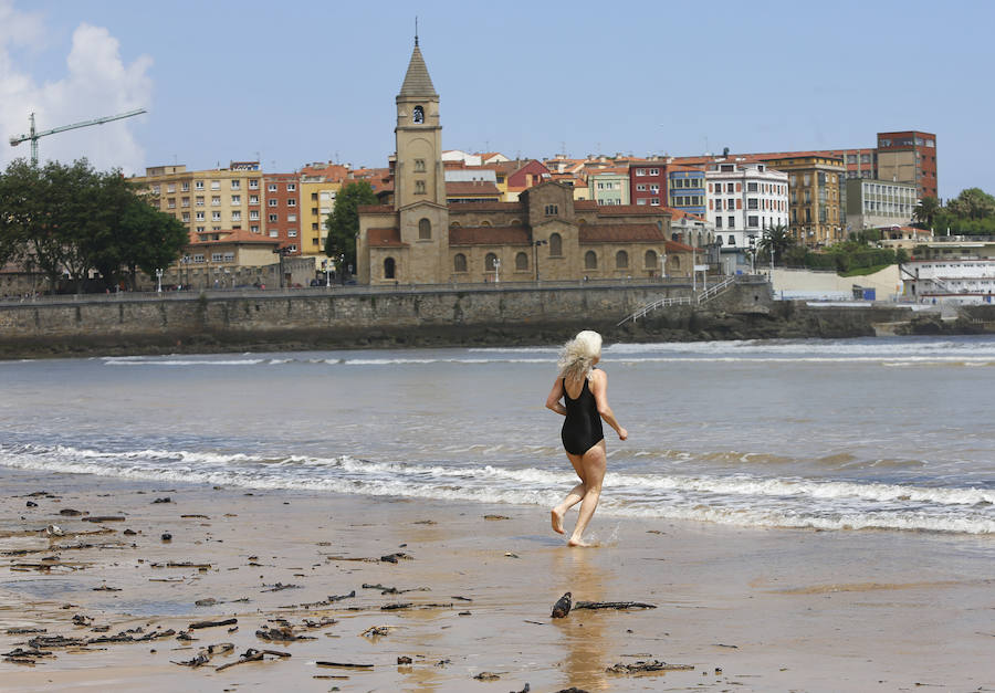 Las banderas amarilla y verde que luce la playa y la buena temperatura ya ha animado a algunas personas a pegarse un baño en el Cantábrico. 