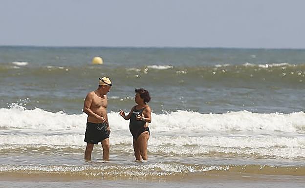 Imagen. Una pareja conversa tras adentrarse en el agua a la altura de la escalera 4. 