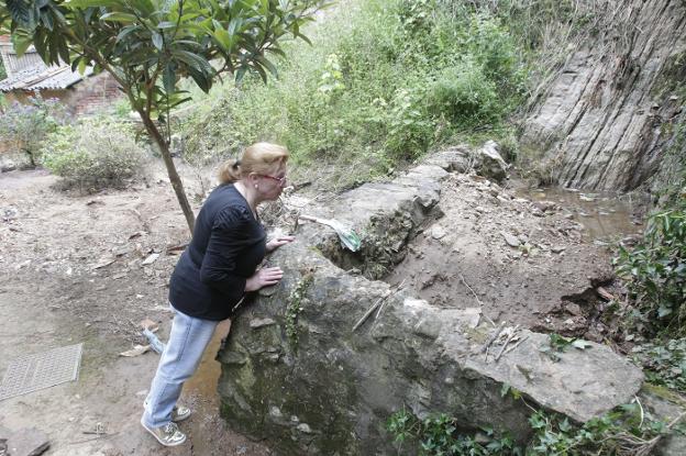 Loli Segovia junto al reguero «colapsado» de lodo y piedras que comunica con el pozo en su vivienda del barrio de Cataluña en Trubia. 