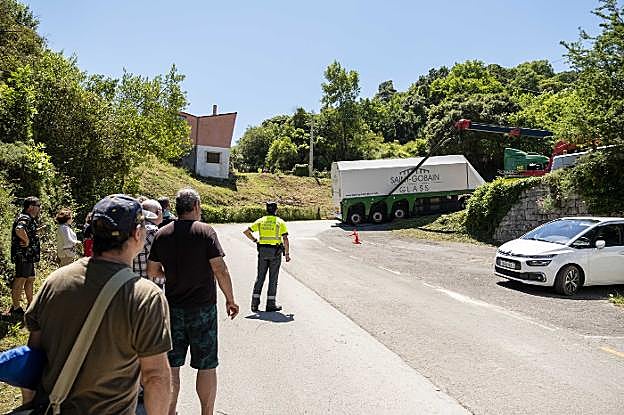 Varias personas contemplan, tras un agente de la Guardia Civil, las maniobras para liberar al camión. 