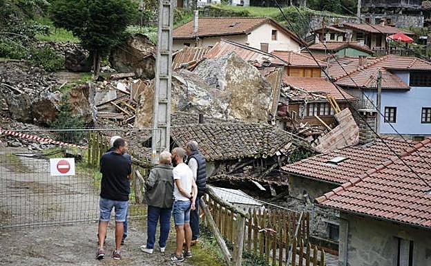 Unos vecinos revisan la zona destrozada por el argayo en La Cortina.